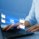 Side view of man on computer with graphics hovering over keyboard, displaying folder file transfer